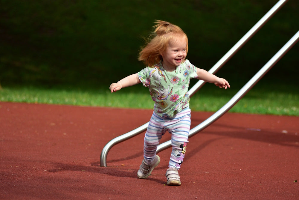 This happy toddler is playing on a rubber mulch playground that is safe and non-toxic
