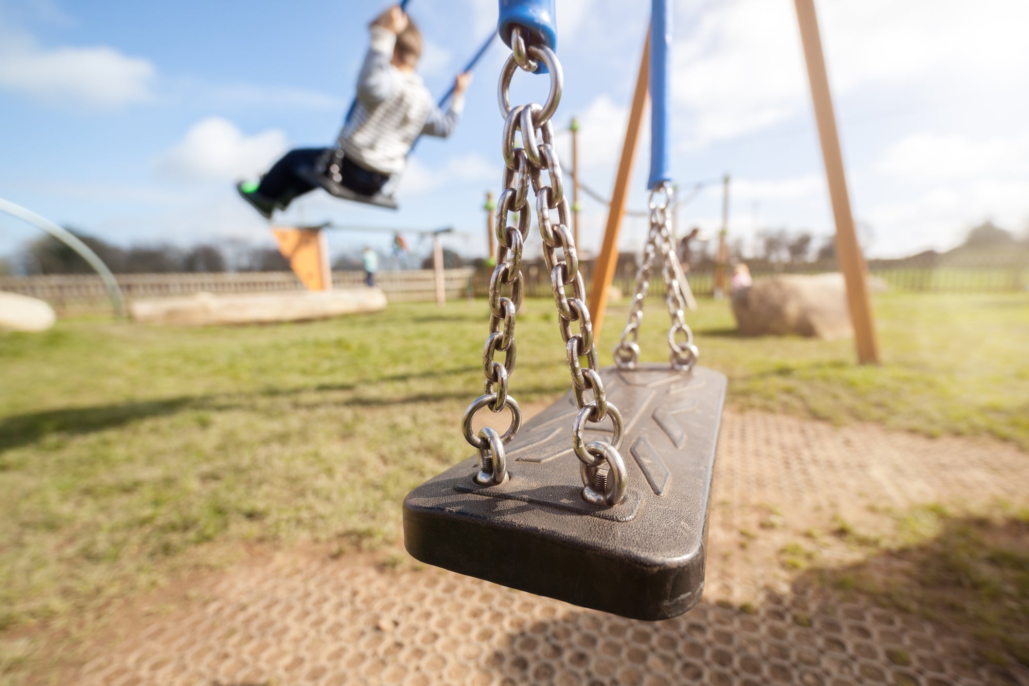 playground swing with child swinging in background