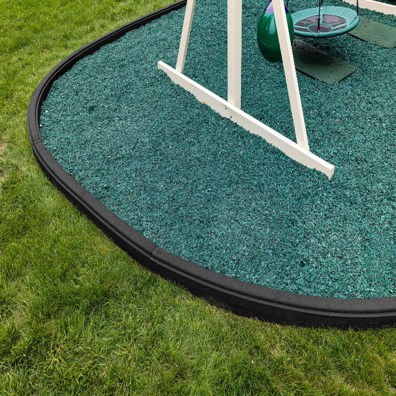 Swing set on a green rubber mat with grass around